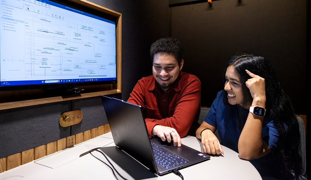 Two students working together with a computer in a study room.