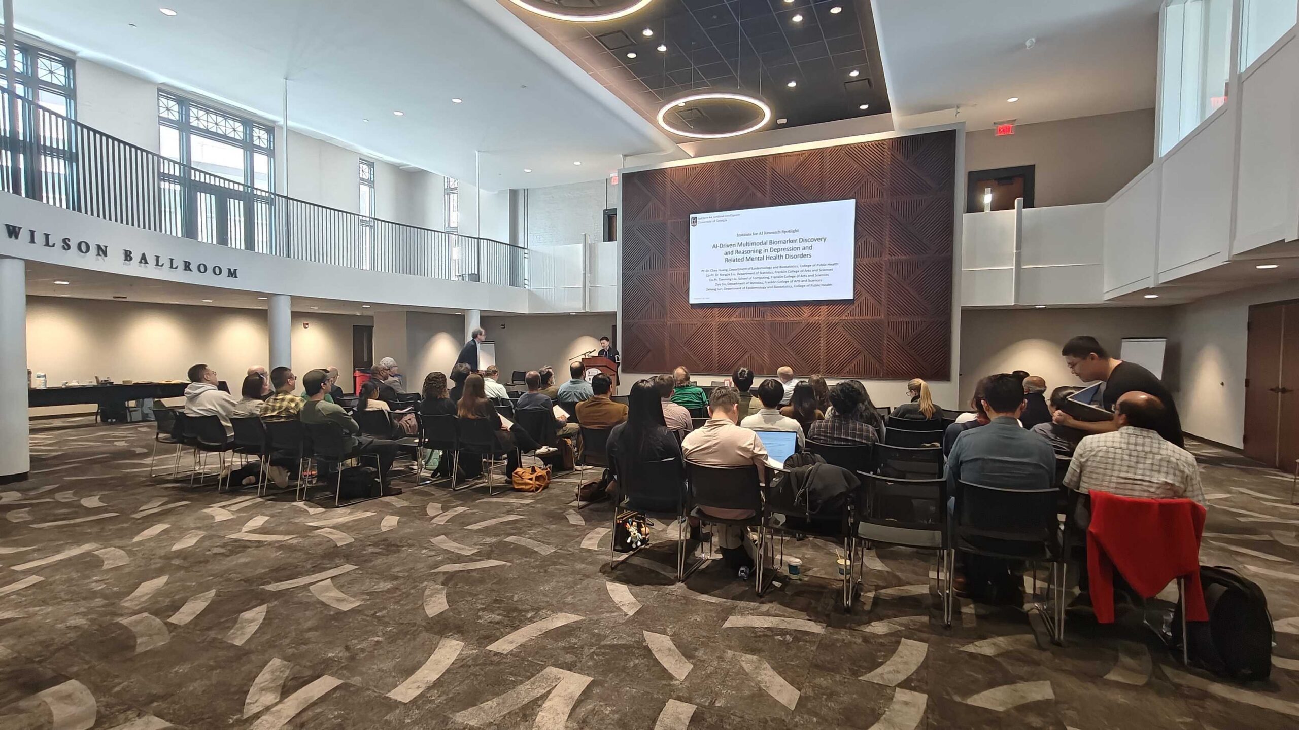 A group of people listening to a presentation in a large meeting room